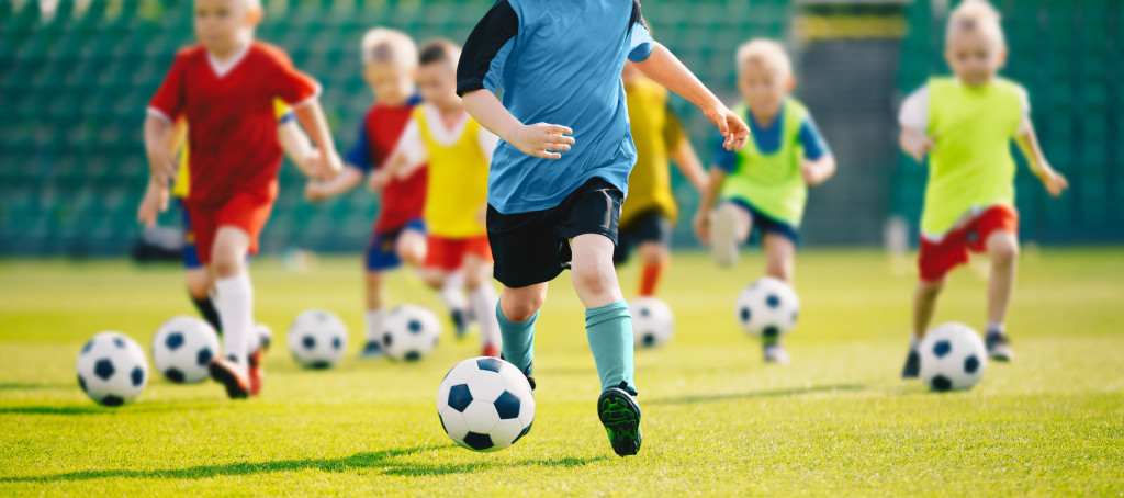 Football soccer training for kids. Children football training session. Kids running and kicking soccer balls. Young boys improving soccer skills